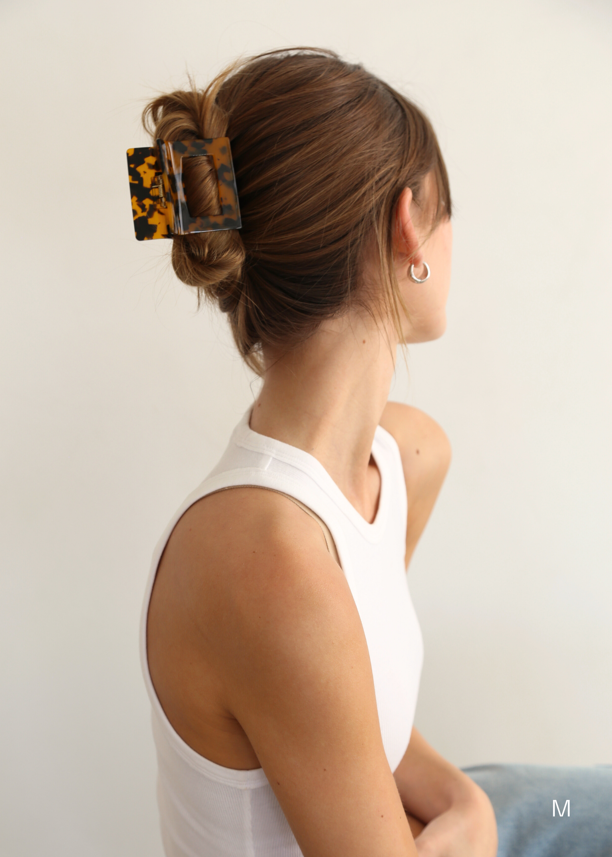 Woman with chestnut coloured hair in an up do hairstyle secured with a dark tortoise, square shaped hair claw clip.