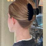 Woman with blonde hair styled with a  black claw clip in an urban setting