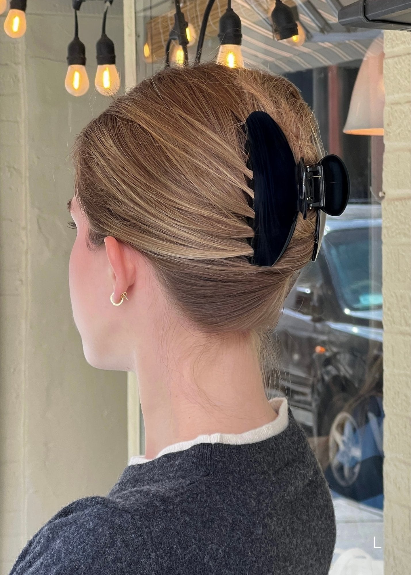 Woman with blonde hair styled with a  black claw clip in an urban setting