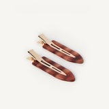 Two small hair clips in a honey colour with gold hardware on a white background
