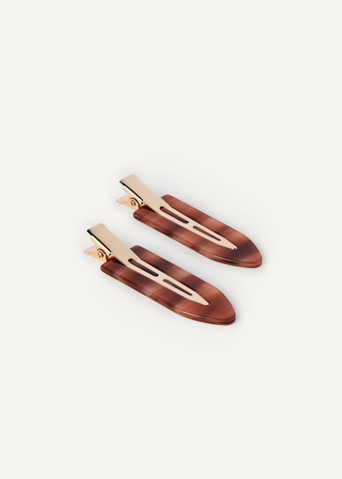 A pair of the Creaseless Clips in Honey, small hair clips, with gold hardware on a white background