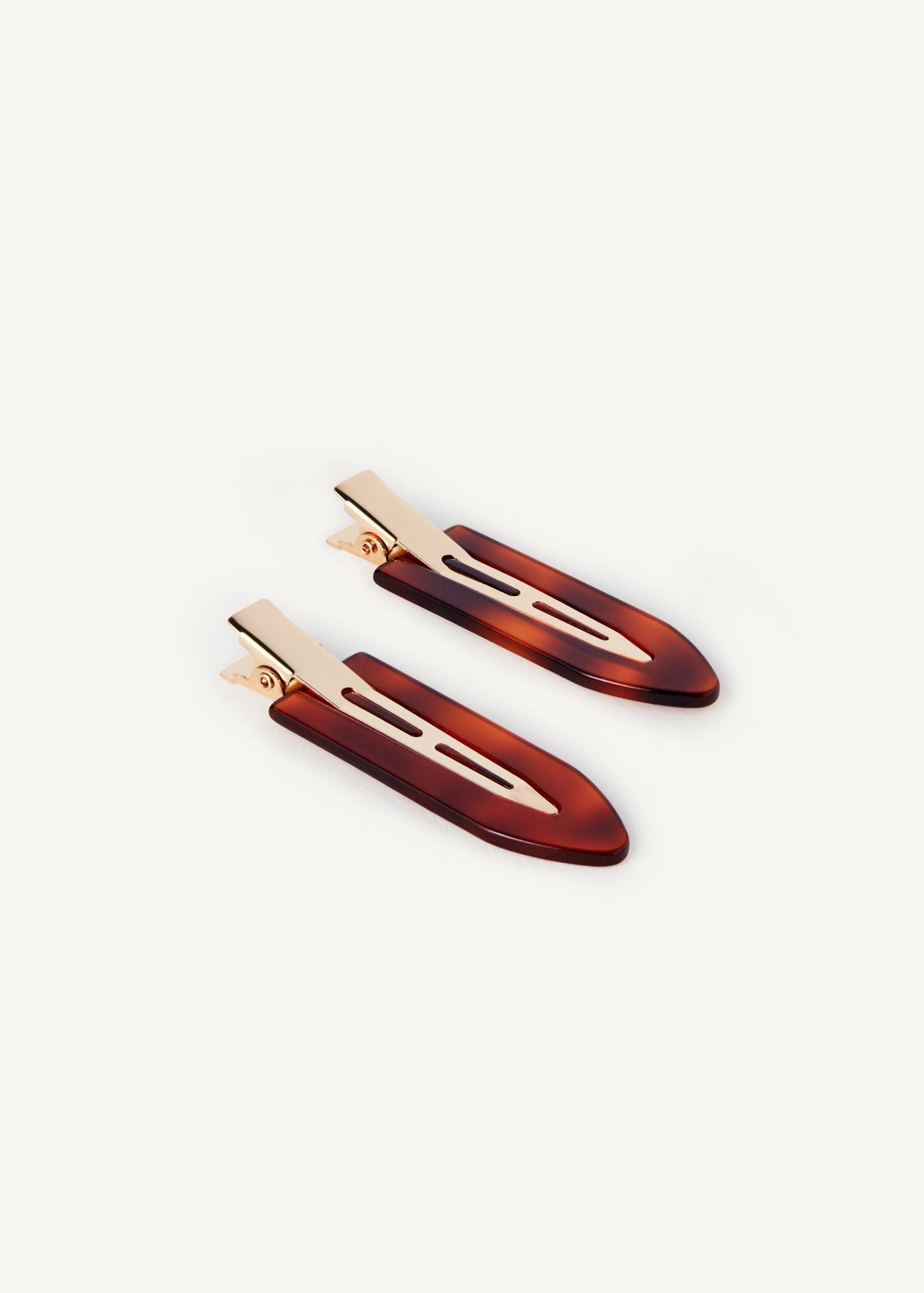 A pair of Creaseless Clips in Spice, a small hair clips, with gold hardware on a white background