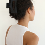 Woman with a black hair clip in her curly hair against a white background