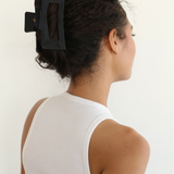 Woman with a black hair clip in her curly hair against a white background
