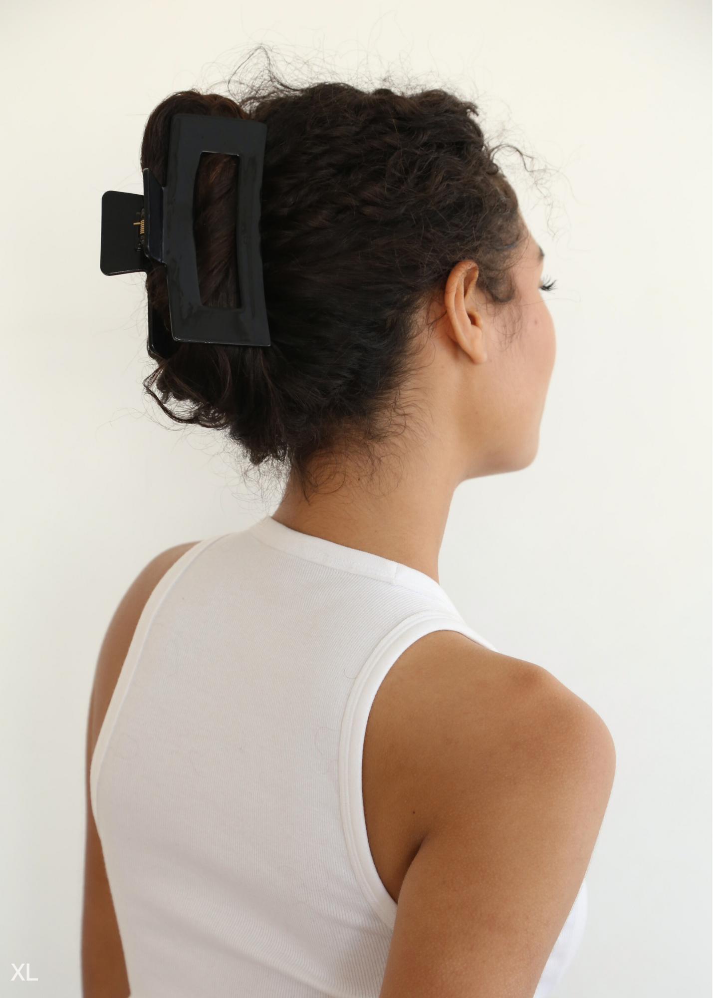 Woman with a black hair clip in her curly hair against a white background
