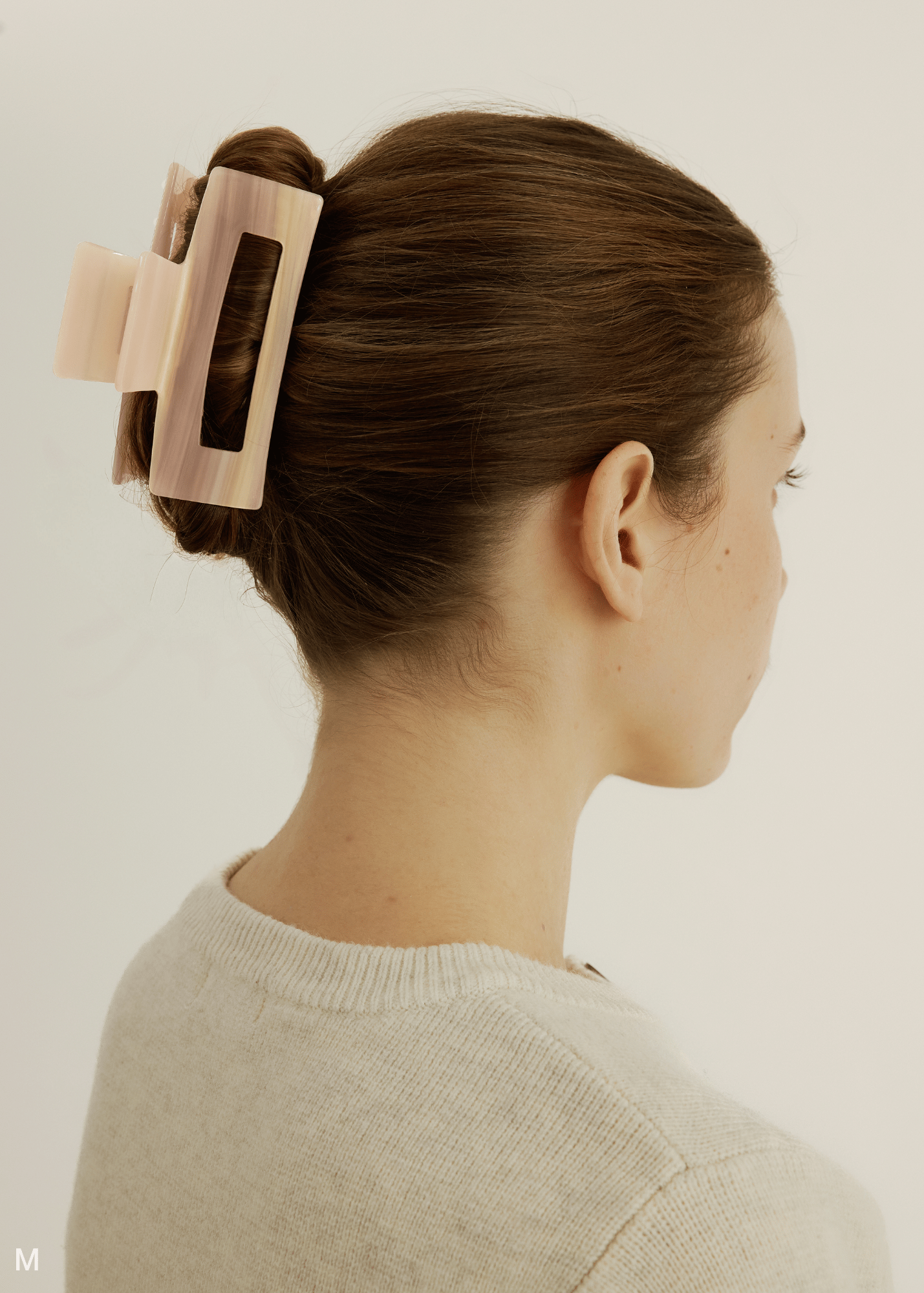 Woman wearing a pink hair clip on a white background.