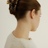 Woman wearing a tortoiseshell hair clip on a plain background