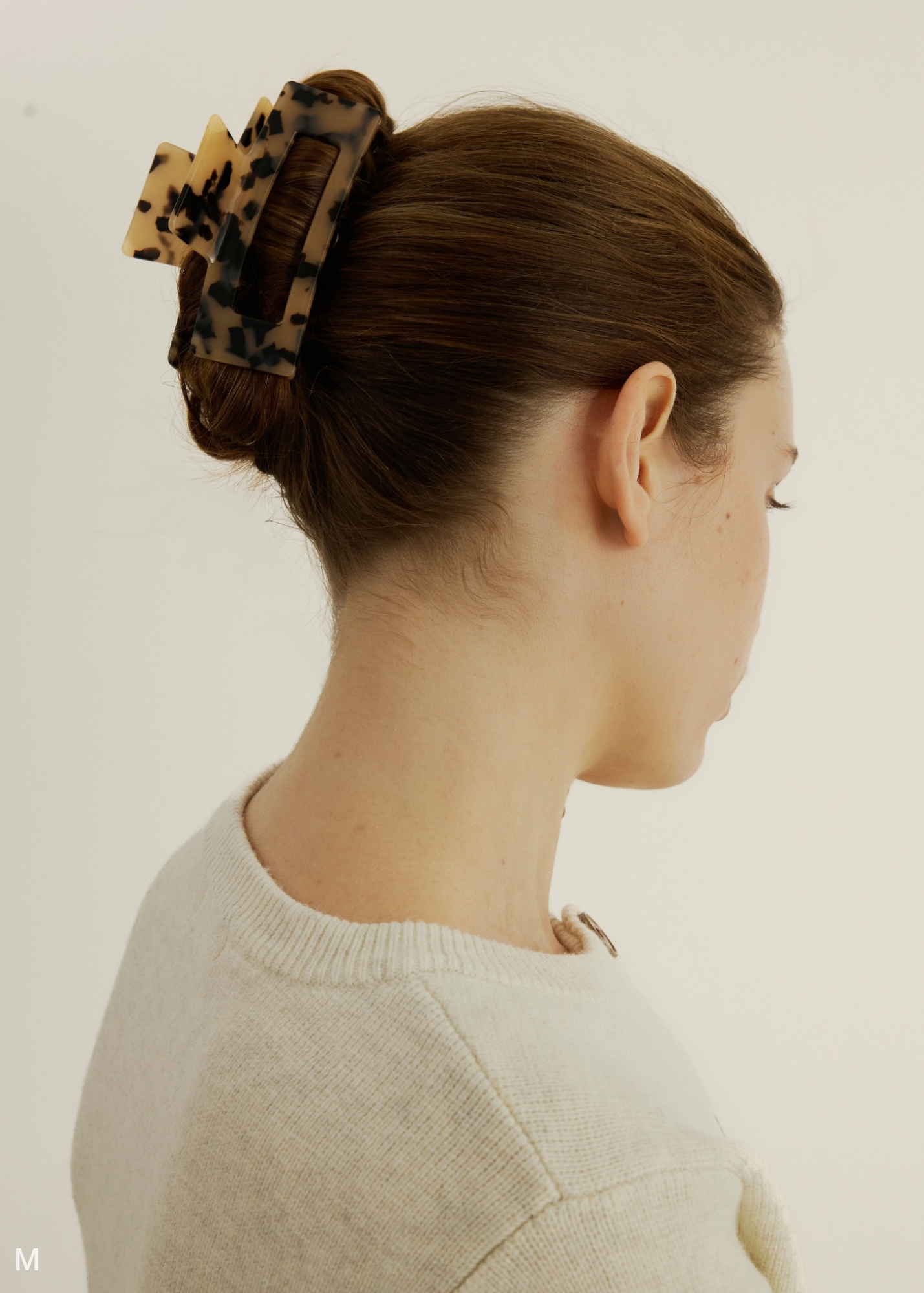 Woman wearing a tortoiseshell hair clip on a plain background