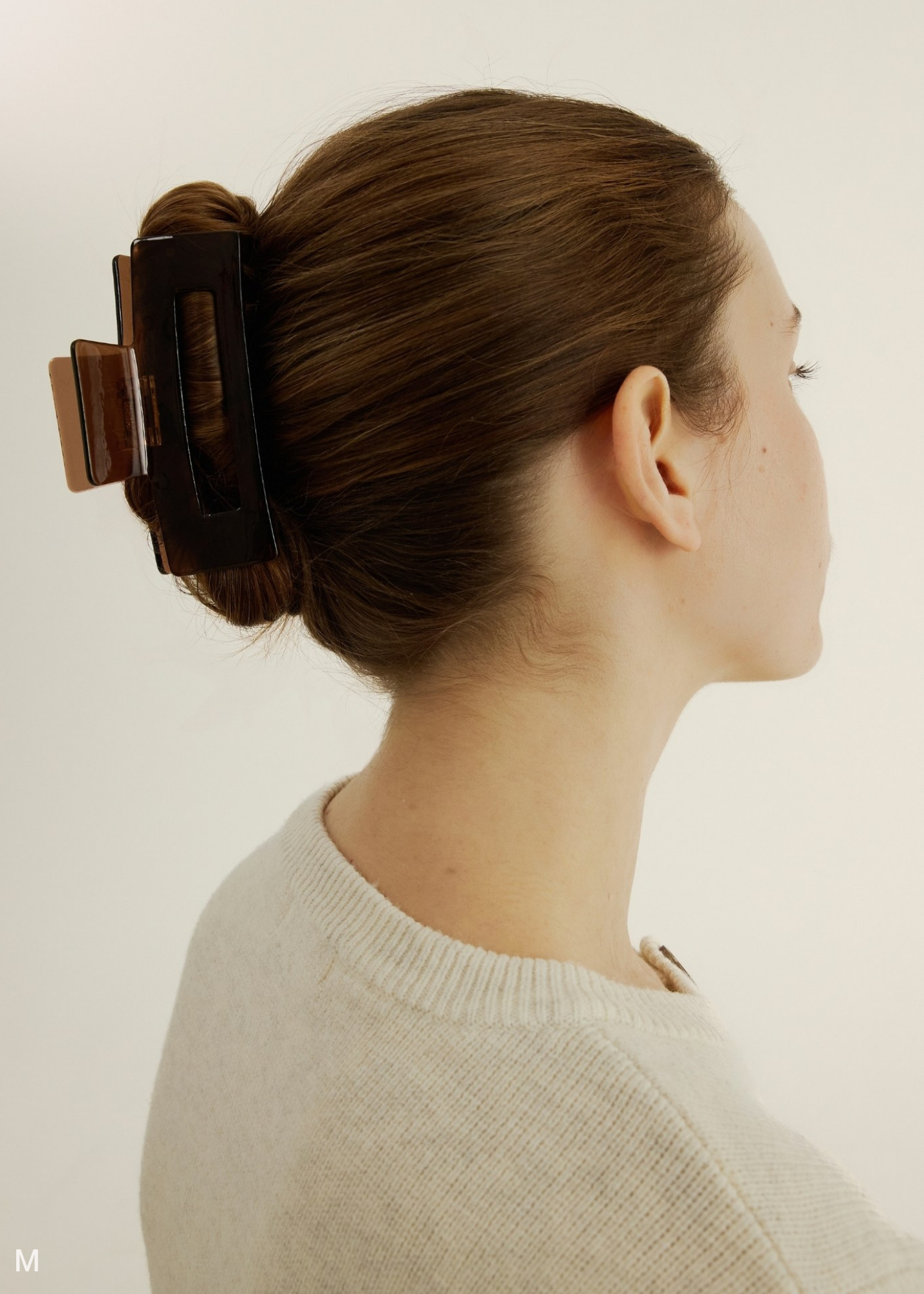 Woman wearing a brown hair clip on a plain background