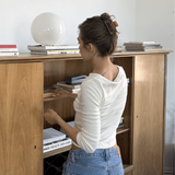 Woman organizing items inside a wooden cabinet wearing a caramel coloured hair clip.