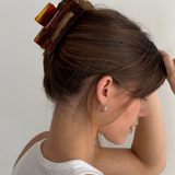 Woman with a red-toned neutral hair clip in her bun against a plain background