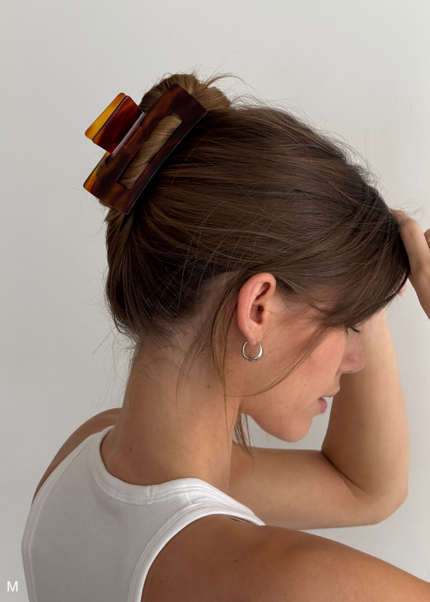 Woman with a red-toned neutral hair clip in her bun against a plain background