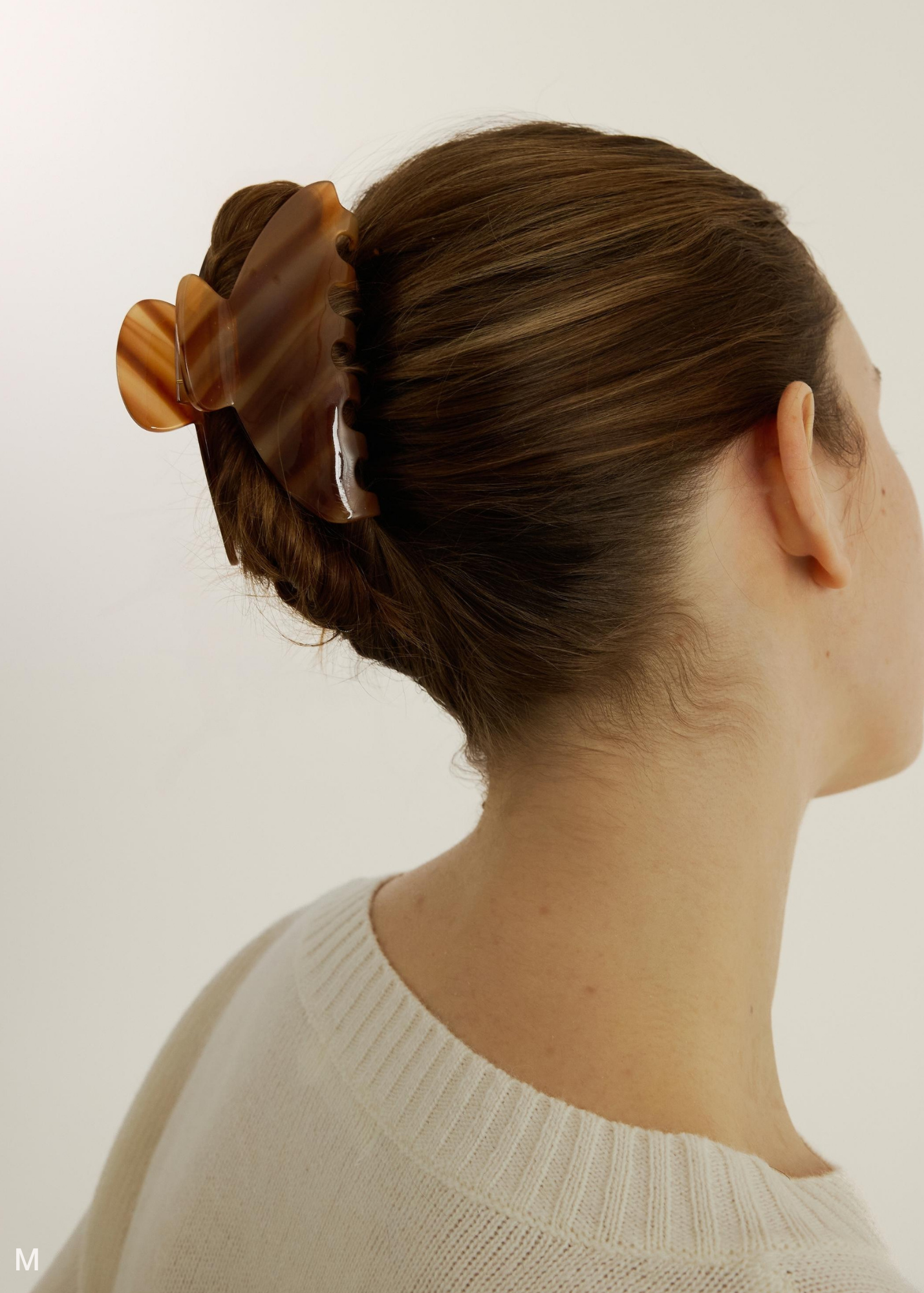 Woman with a caramel coloured hair clip against a plain background