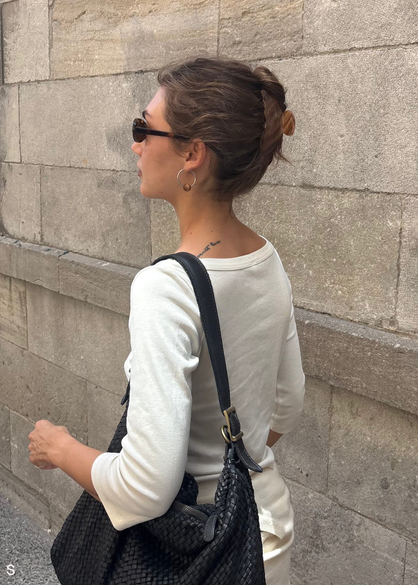 Woman in a small caramel coloured claw clip against a stone wall.