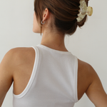 Woman wearing a cream claw clip against a plain background.