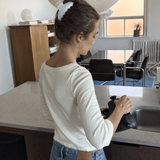 Woman washing dishes in a kitchen wearing a medium pearl claw clip.