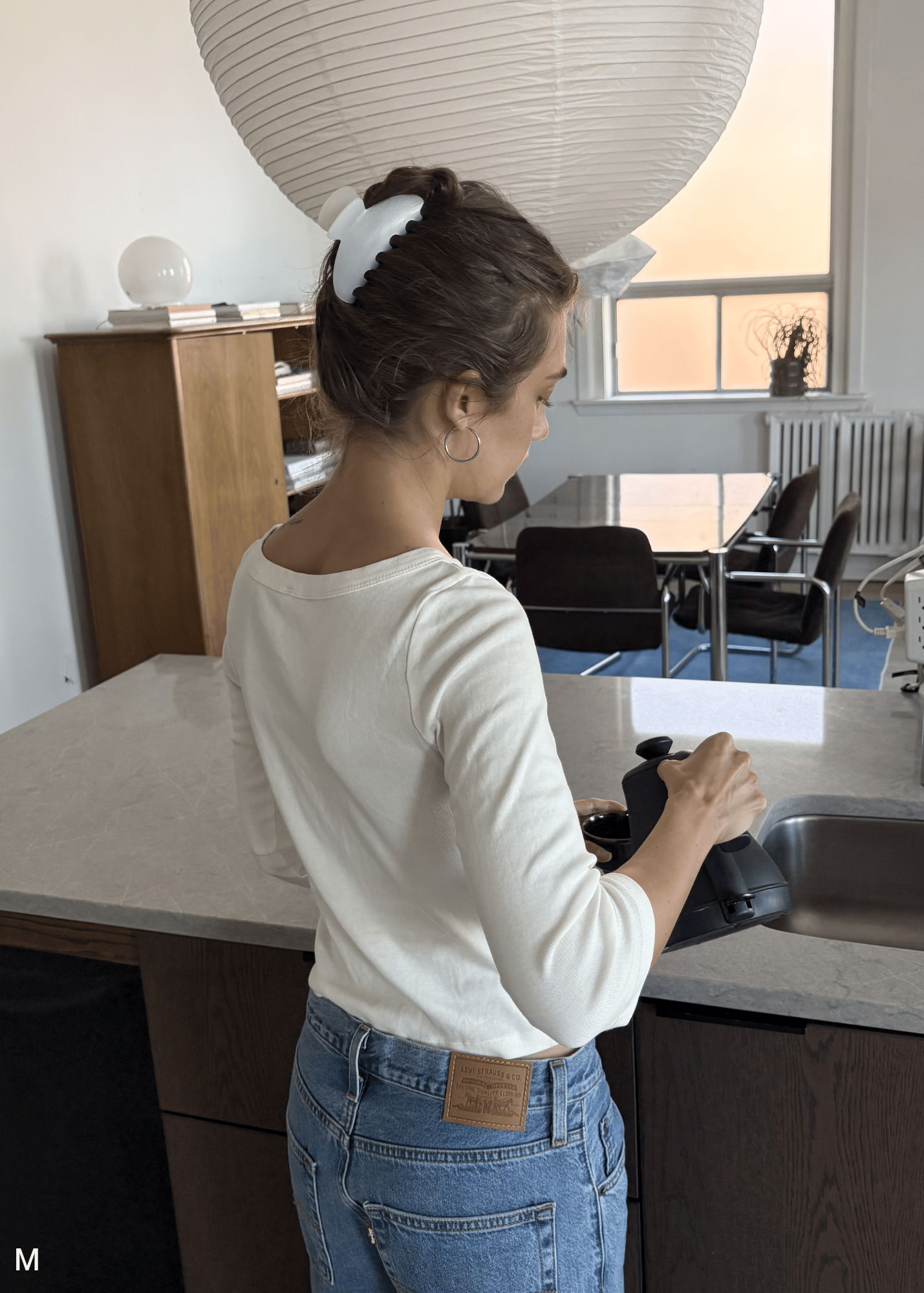 Woman washing dishes in a kitchen wearing a medium pearl claw clip.
