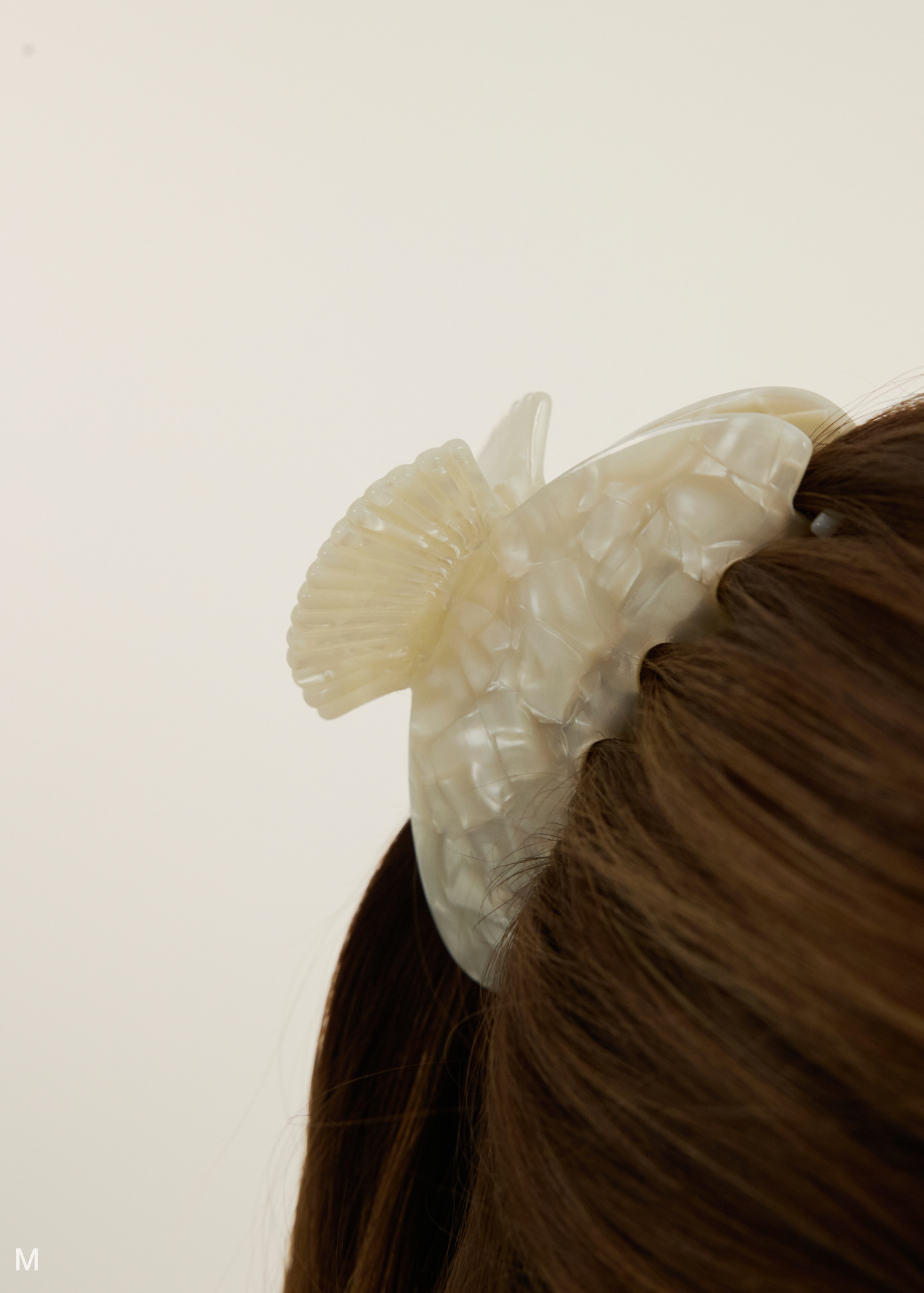 Close up on a mother of pearl hair clip with shell detailing on the handle in brown hair.