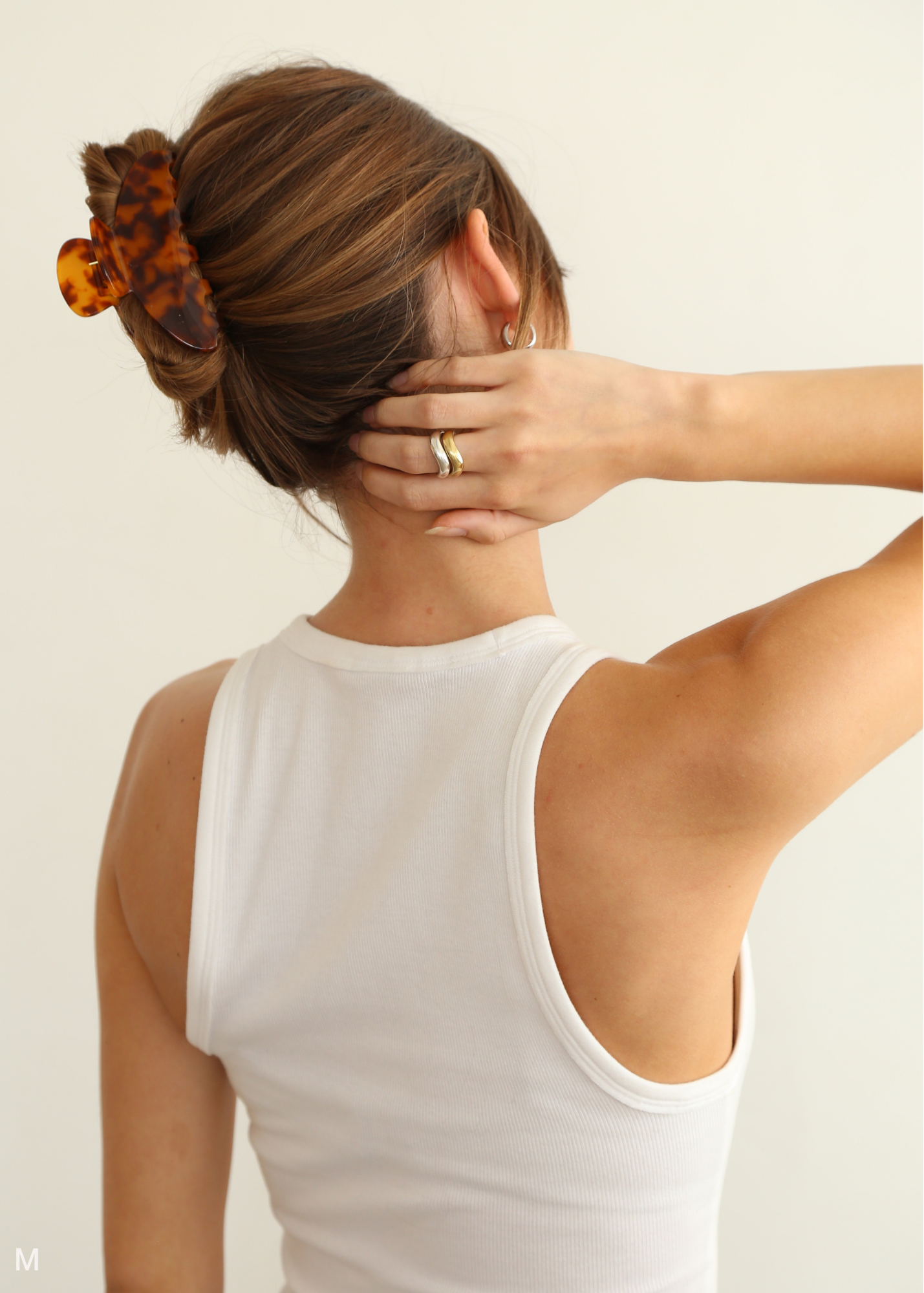Person with brown hair wearing a medium sized tortoiseshell claw clip against a white background