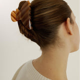 Woman with an up-do hairstyle secured with the large Demi Clip in Honey wearing a white top on a white background
