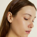 Close-up of a woman with a honey-coloured headband on a plain background