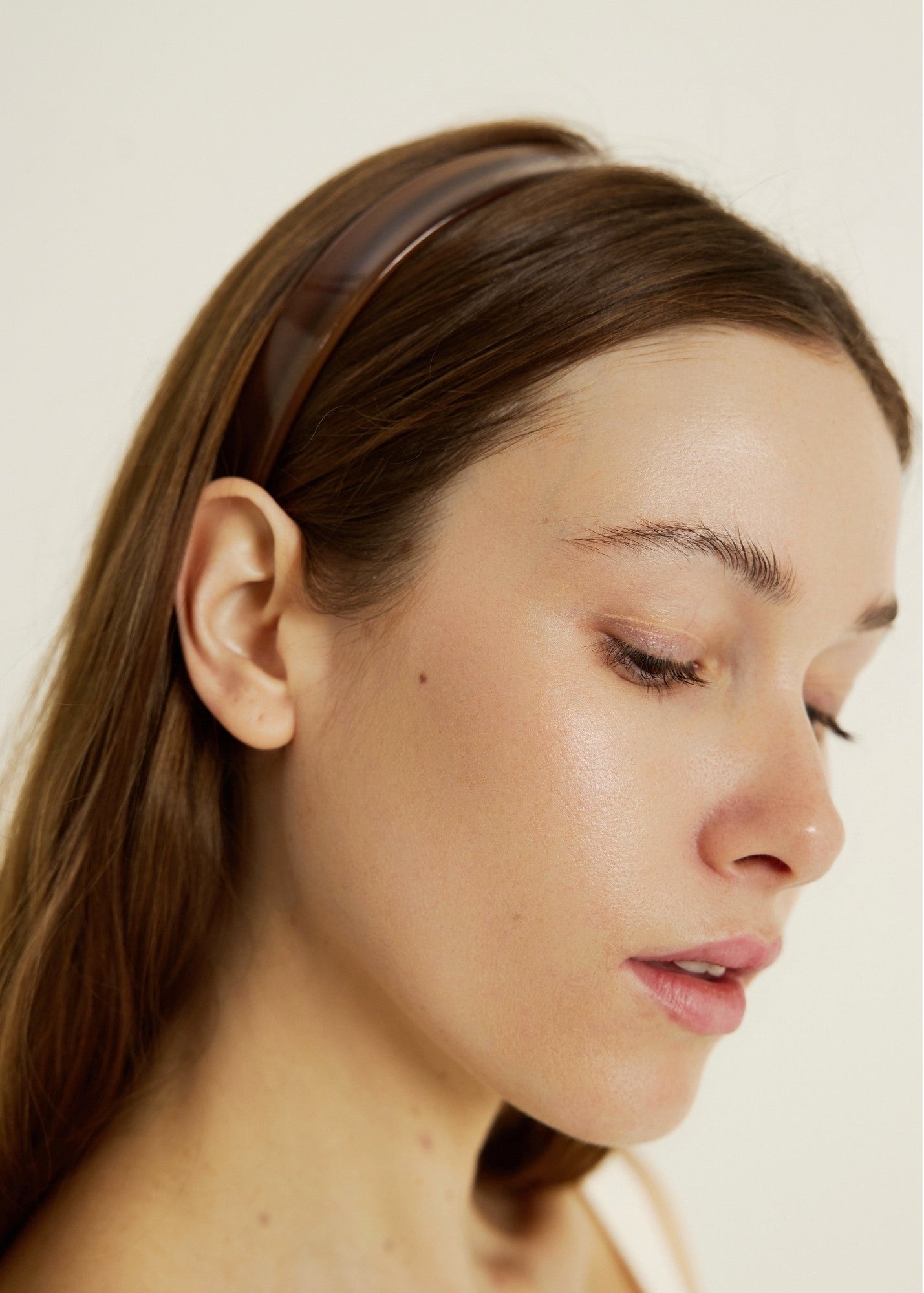 Close-up of a woman with a honey-coloured headband on a plain background