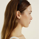 Woman with long hair wearing a dark reddish headband against a plain background