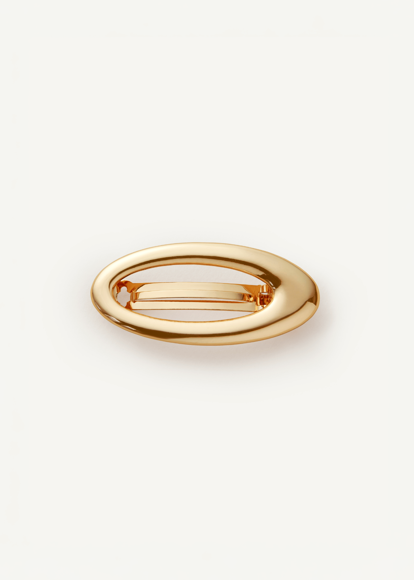 Gold metal barrette with a cutout in the middle on a white background