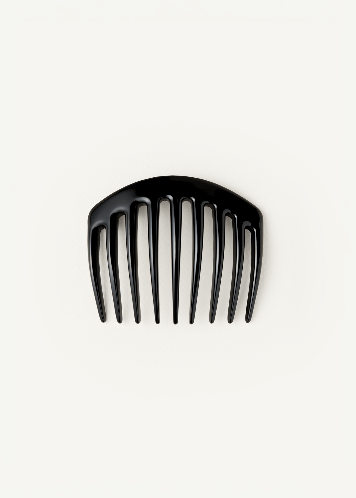 A large, slightly curved, black hair comb on a neutral background.