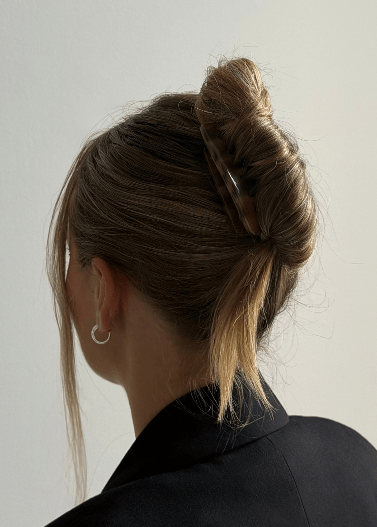A blonde woman 3/4 from the back wearing her hair in a French twist, secured with a French comb
