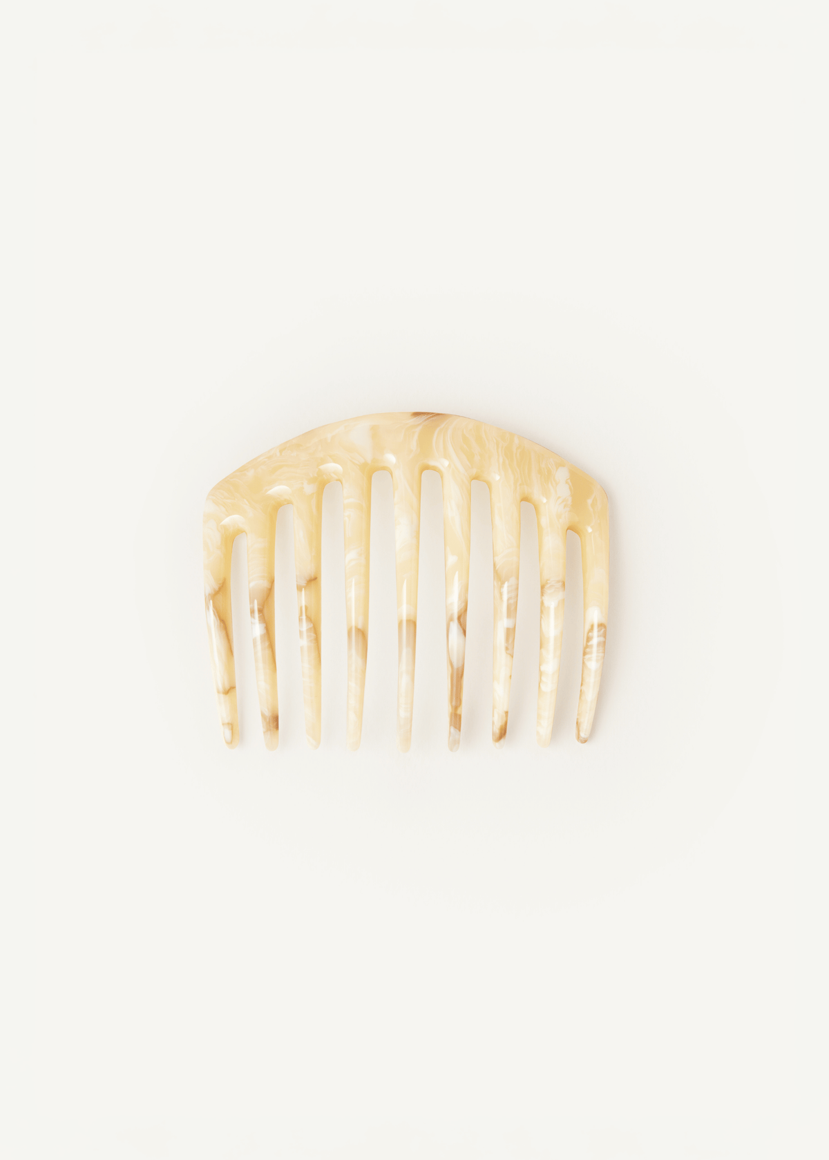 A large, slightly curved, light neutral hair comb on a neutral background