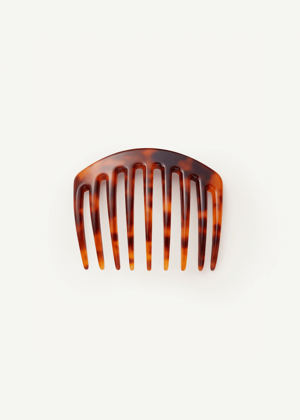 A large, slightly curved hair comb in a tortoiseshell pattern against a neutral background