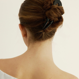 Back view of a person with a black French Pin a plain background.