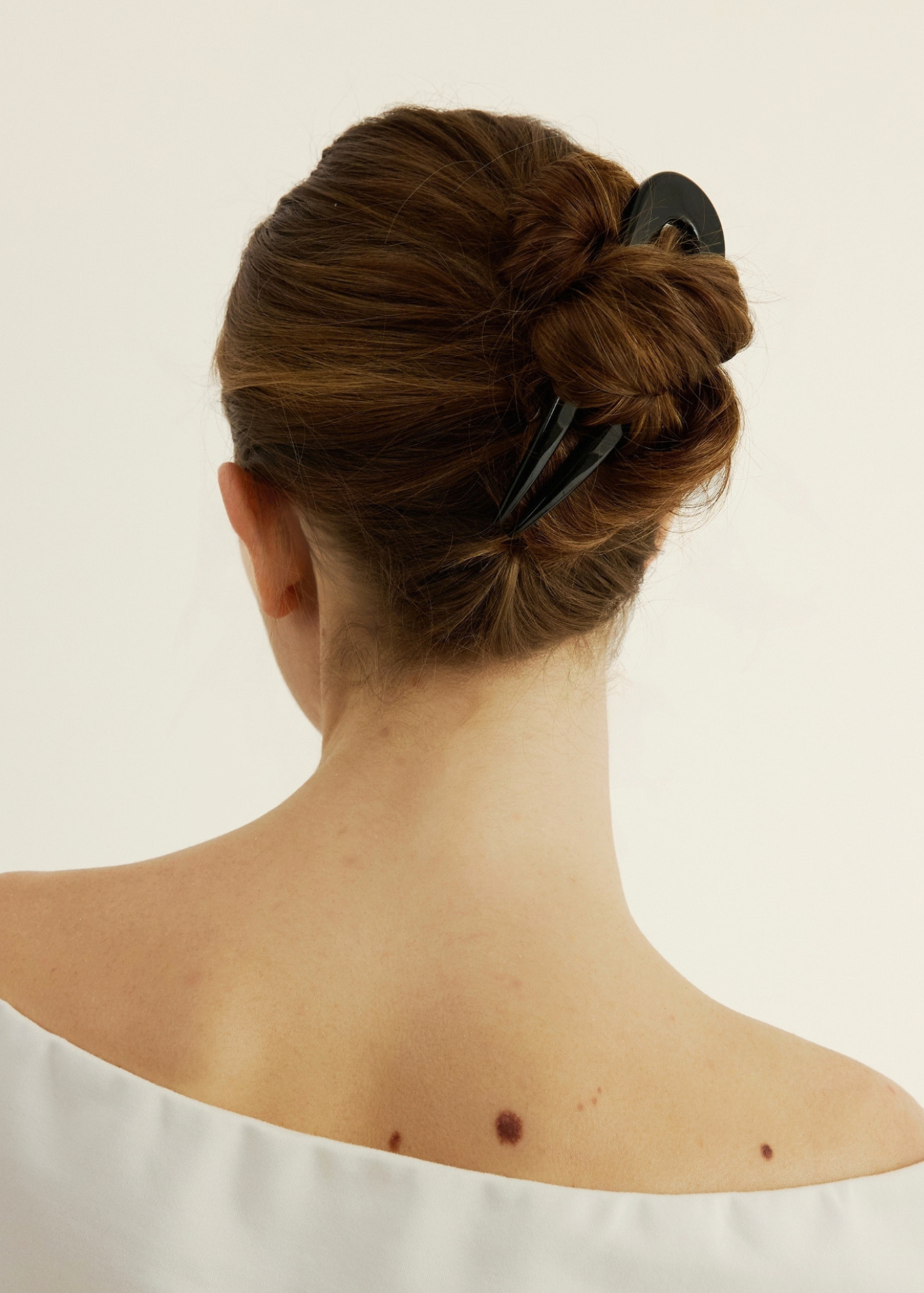 Back view of a person with a black French Pin a plain background.