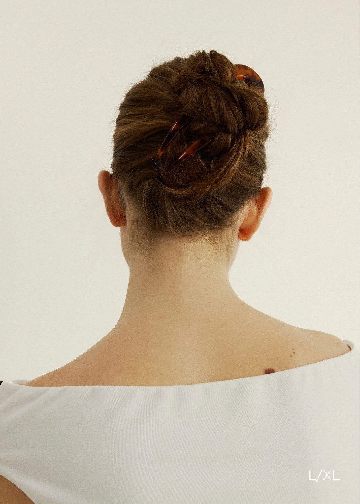 Back view of woman with chestnut coloured hair styled in a bun secured with the French Pin in Tortoise