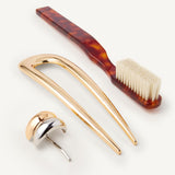 Set of hair accessories including the Detail Brush in Tortoise, French Pin in Gold, and mixed metal hair cuff on a white background.