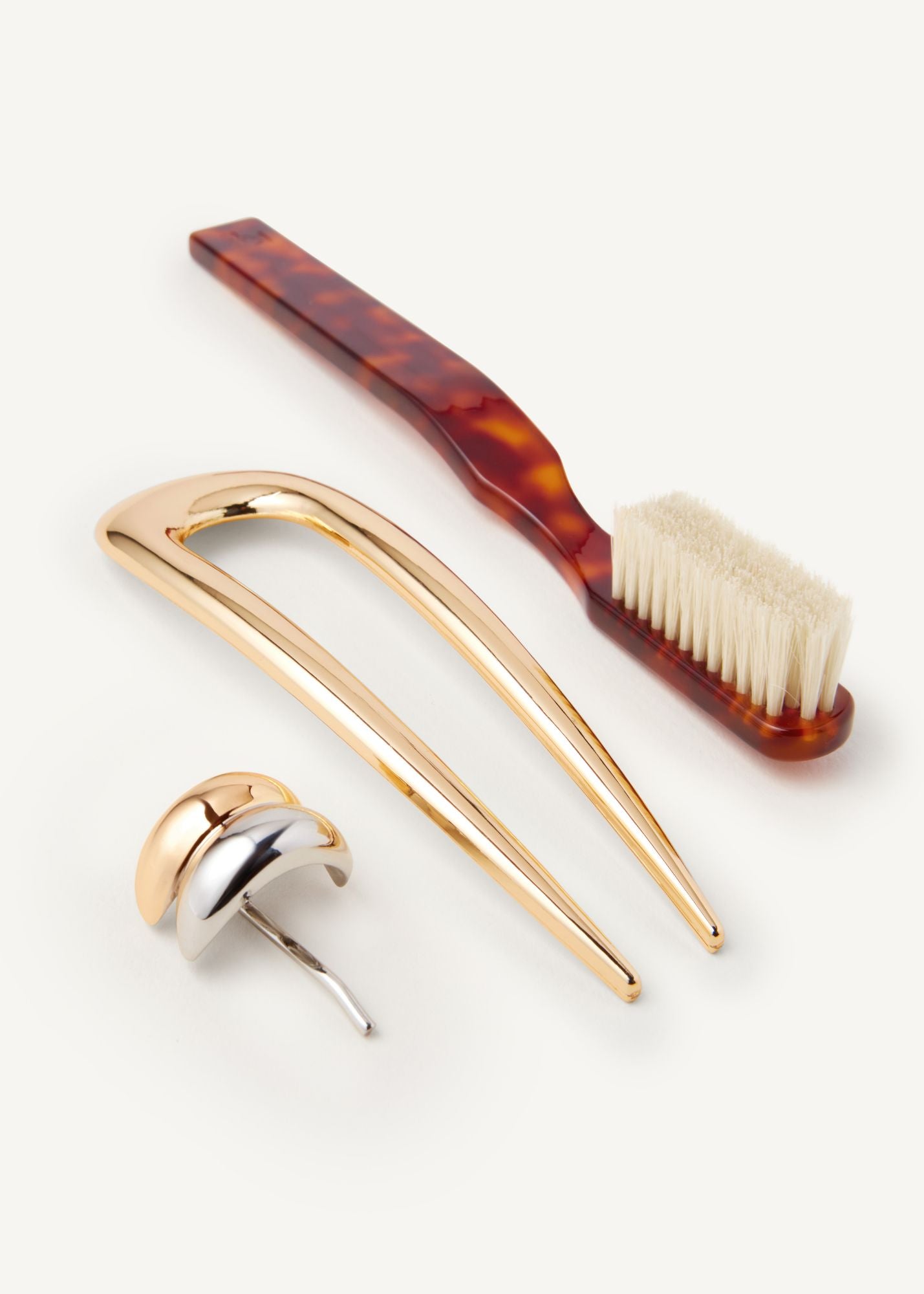 Set of hair accessories including the Detail Brush in Tortoise, French Pin in Gold, and mixed metal hair cuff on a white background.