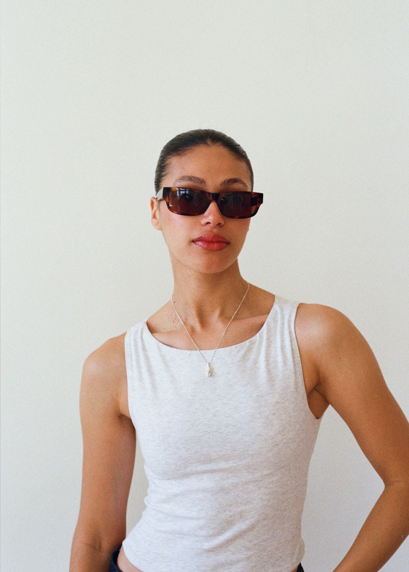 Woman wearing the Haven sunglasses in Tortoise and a white tank top against a plain background