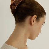 Woman with styled hair using the large Icon Clip in Honey to secure her up-do against a neutral background