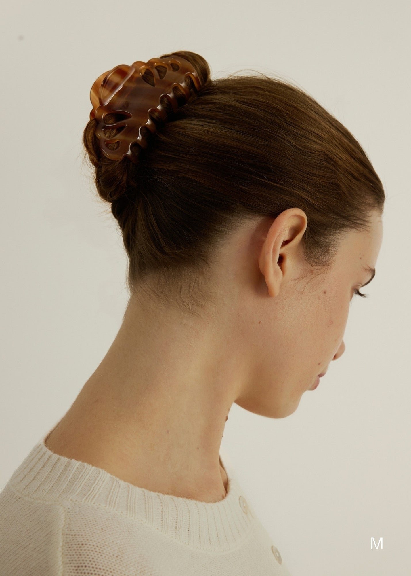 Woman with styled hair using the large Icon Clip in Honey to secure her up-do against a neutral background