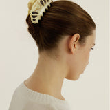 Woman with a decorative hair clip in her bun against a plain background