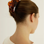 Woman with brown hair styled in an updo secured with a detailed tortoise-coloured claw clip