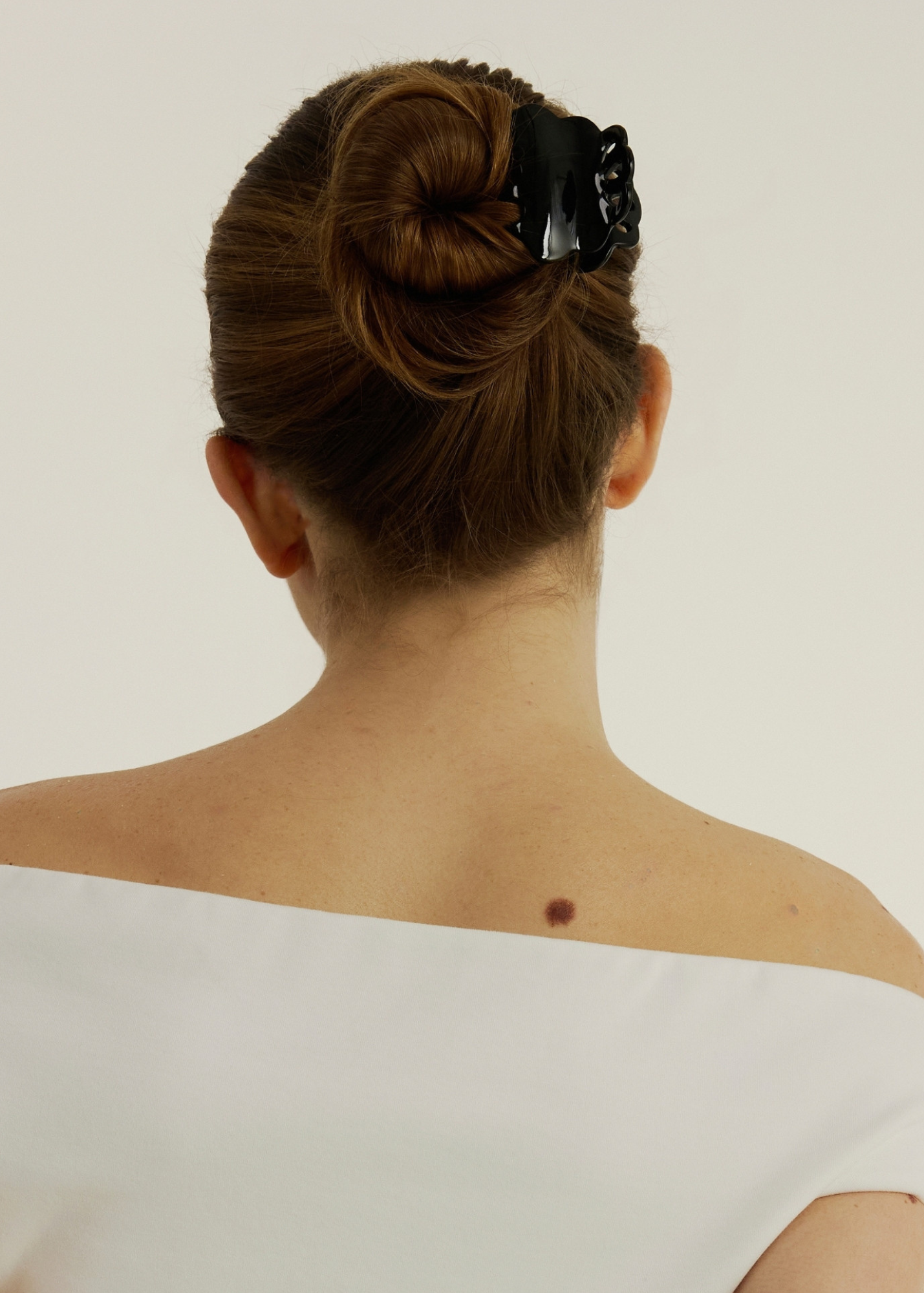 Back view of a person with a neatly styled bun wearing a Black scalloped claw clip.
