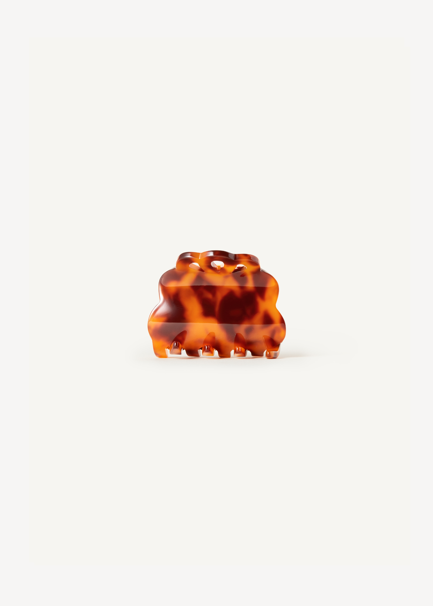 Scalloped, tortoiseshell hair clip on a white background.