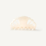 A cream coloured hair clip with cutouts on a white background
