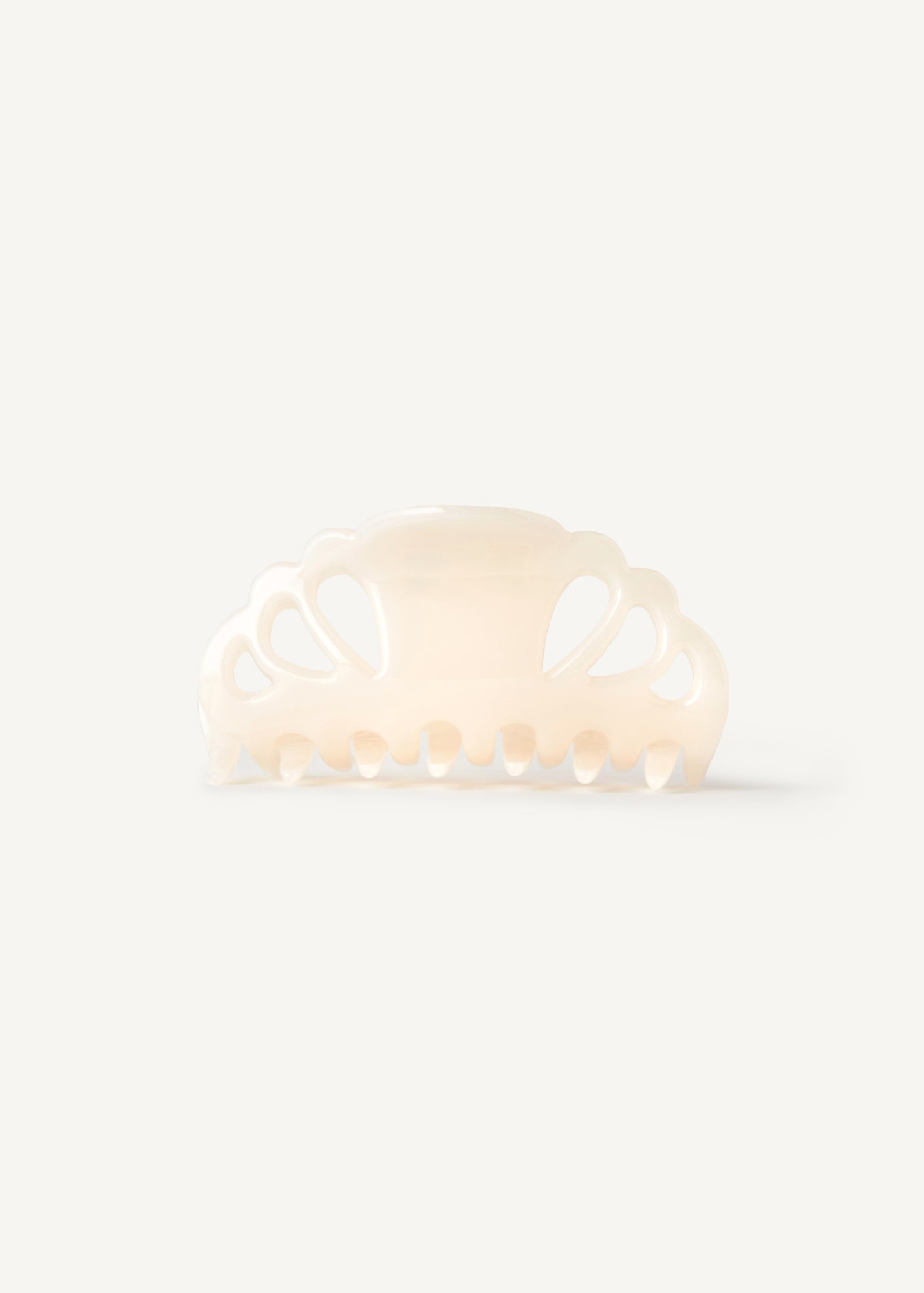 A cream coloured hair clip with cutouts on a white background