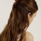 Woman with chestnut coloured hair in a half up, half down hairstyle secured with mini honey coloured hair claw clip.