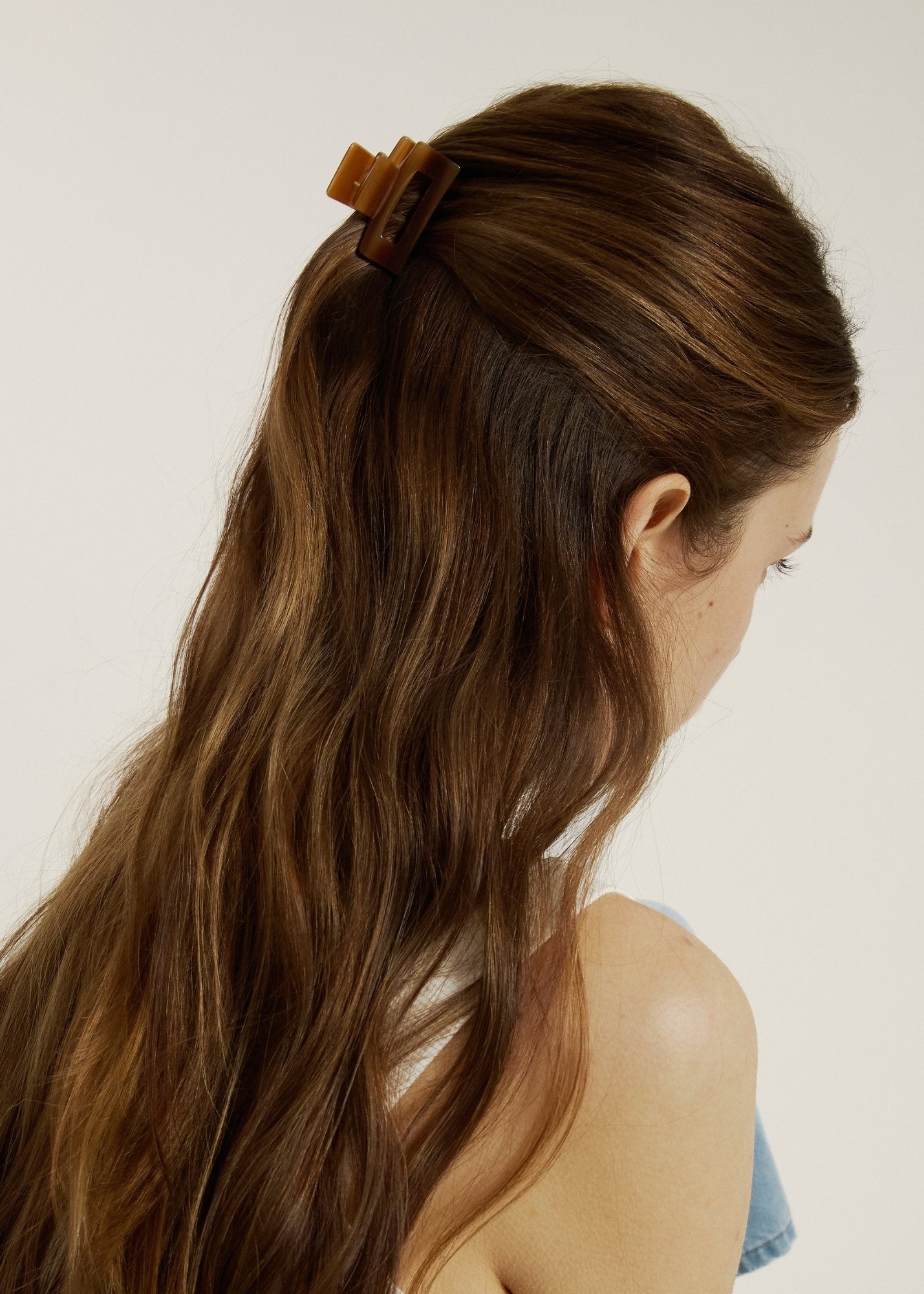 Woman with chestnut coloured hair in a half up, half down hairstyle secured with mini honey coloured hair claw clip.