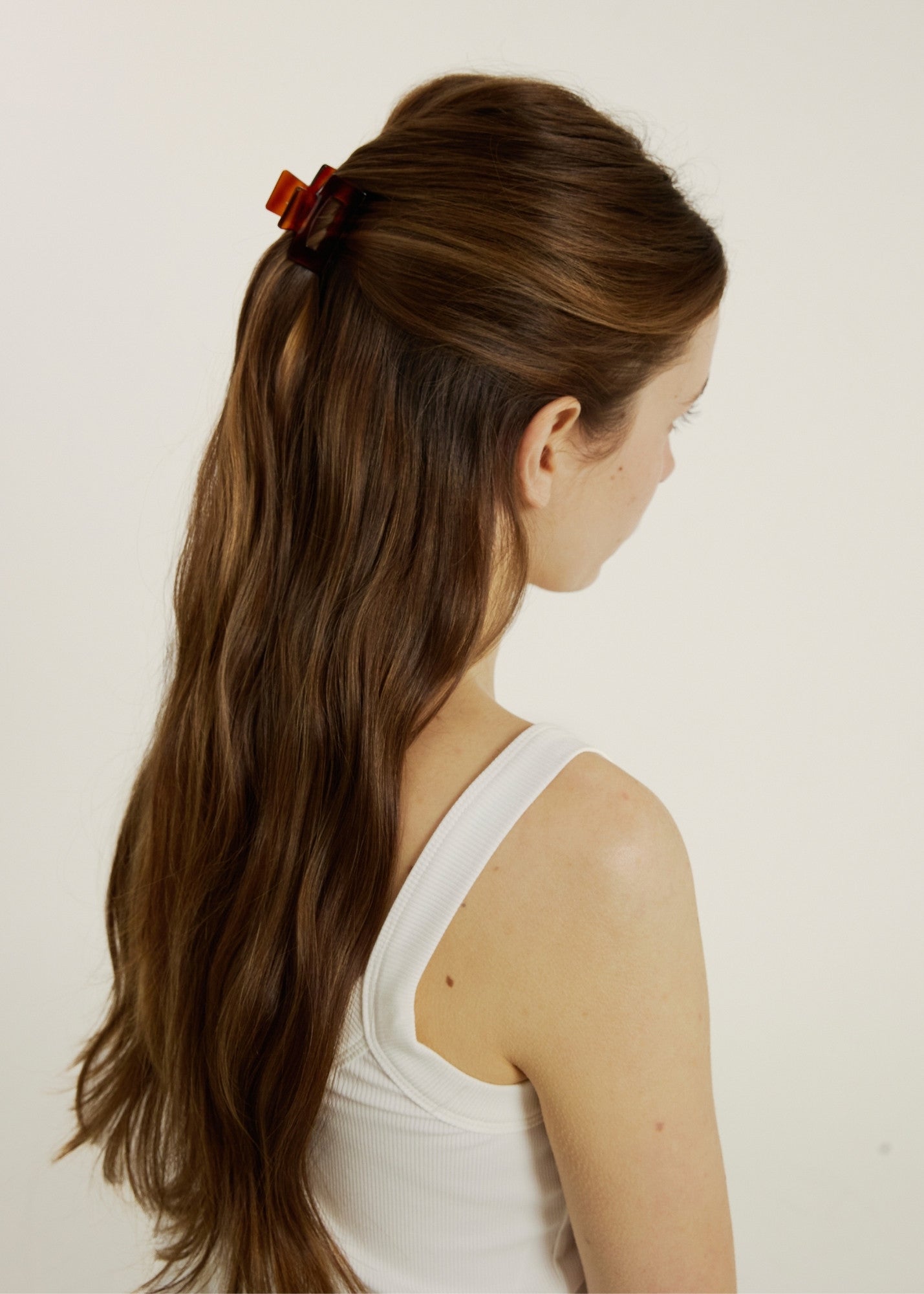 Woman with chestnut coloured hair in a half up, half down hairstyle secured with dark tortoise coloured mini hair claw clip.