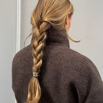 Woman with a braided hairstyle featuring the mixed metal hair cuff, wearing a brown coat against a neutral background